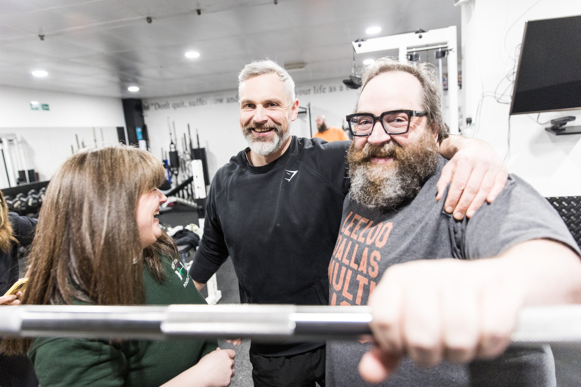 A group of three people smiling in the gym 