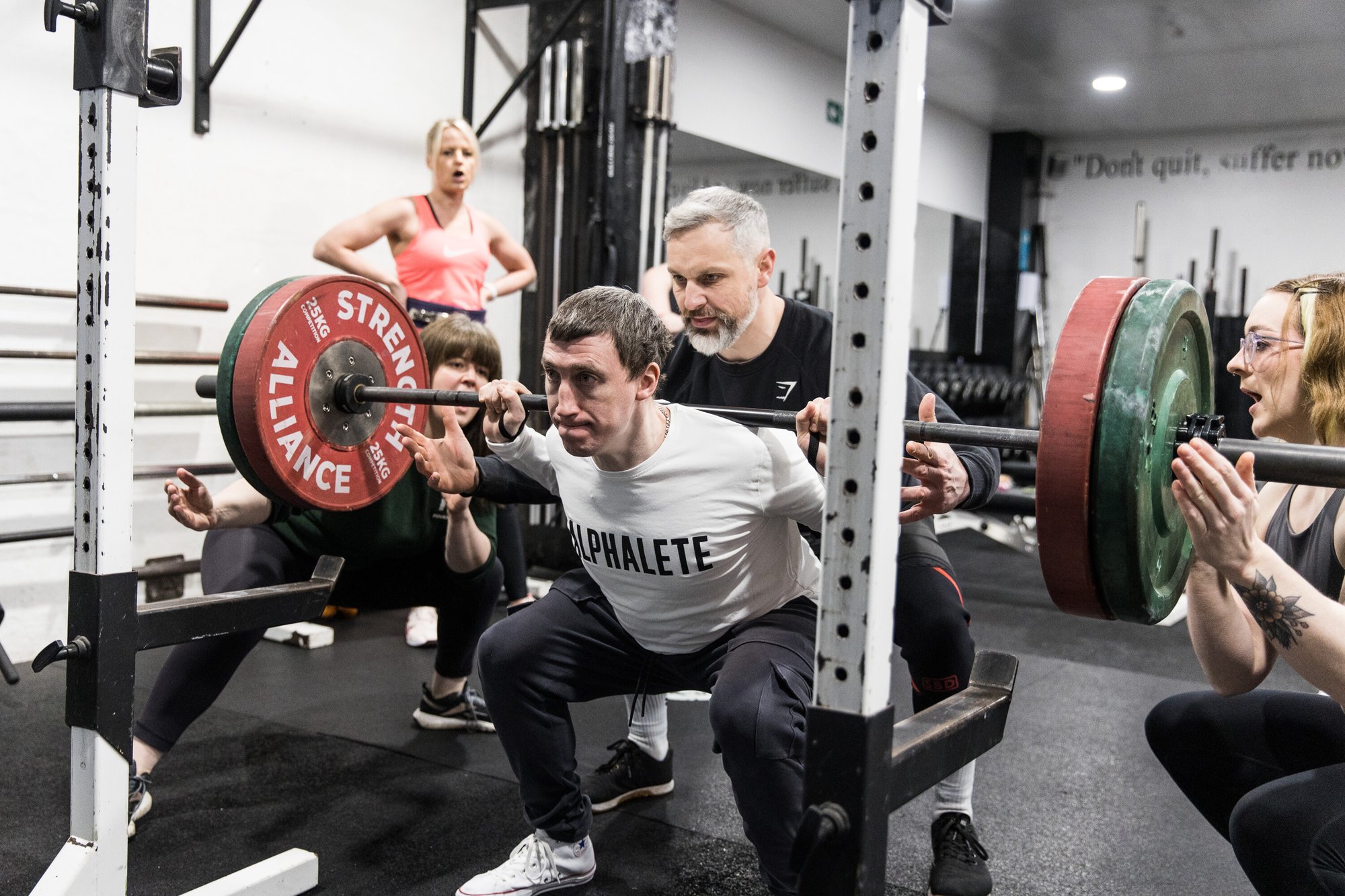 Personal trainer teaching a client to squat in a gym